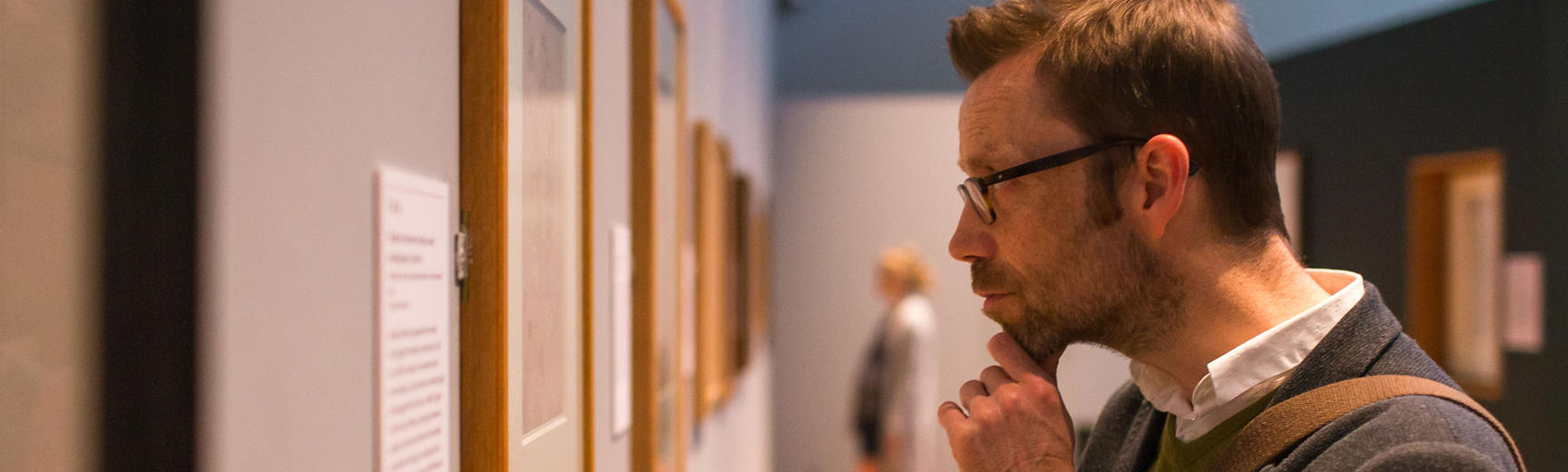 A man takes a closer look at an artwork on display on a gallery wall