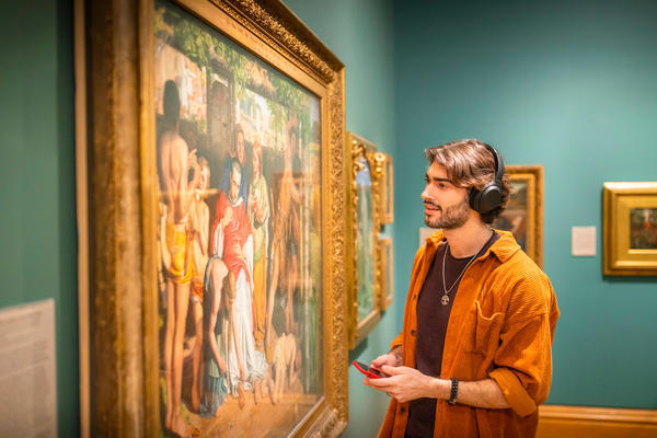 Visitor listening to an autio tour with headphones in the museum galleries